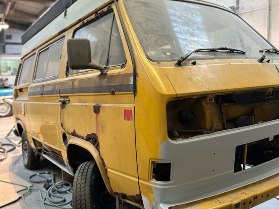 Classic yellow camper undergoing bodywork restoration in the workshop
