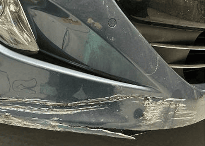 Heavily scuffed front bumper before professional repair and refinishing