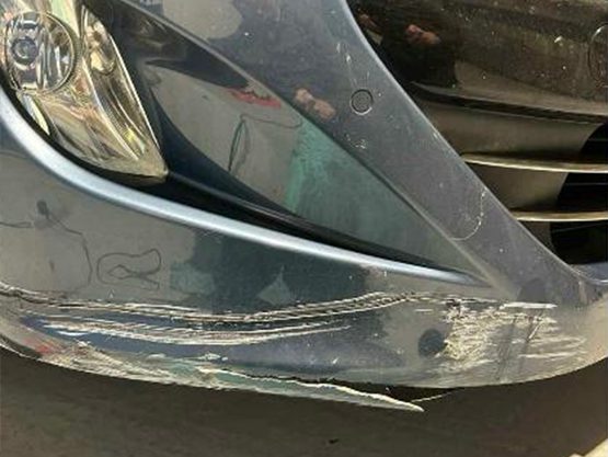 Scraped and scuffed front bumper before repair and refinishing