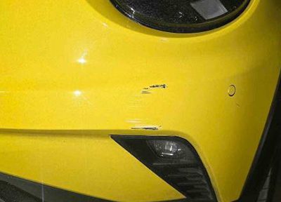 Minor scratches and scuffs on a yellow car bumper before repair