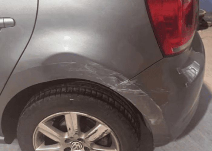 Dent and scuff damage to a car rear quarter panel before body repair